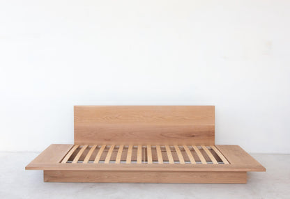 Minimalist white oak platform bed with a plinth base.